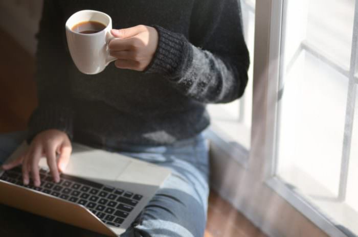 A person working from their laptop as drinking coffee at home during the coronavirus.