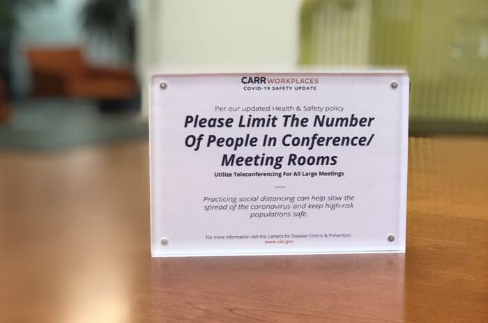 "Please Limit the Number of People in Conference & Meeting Rooms" sign at Carr Workplaces