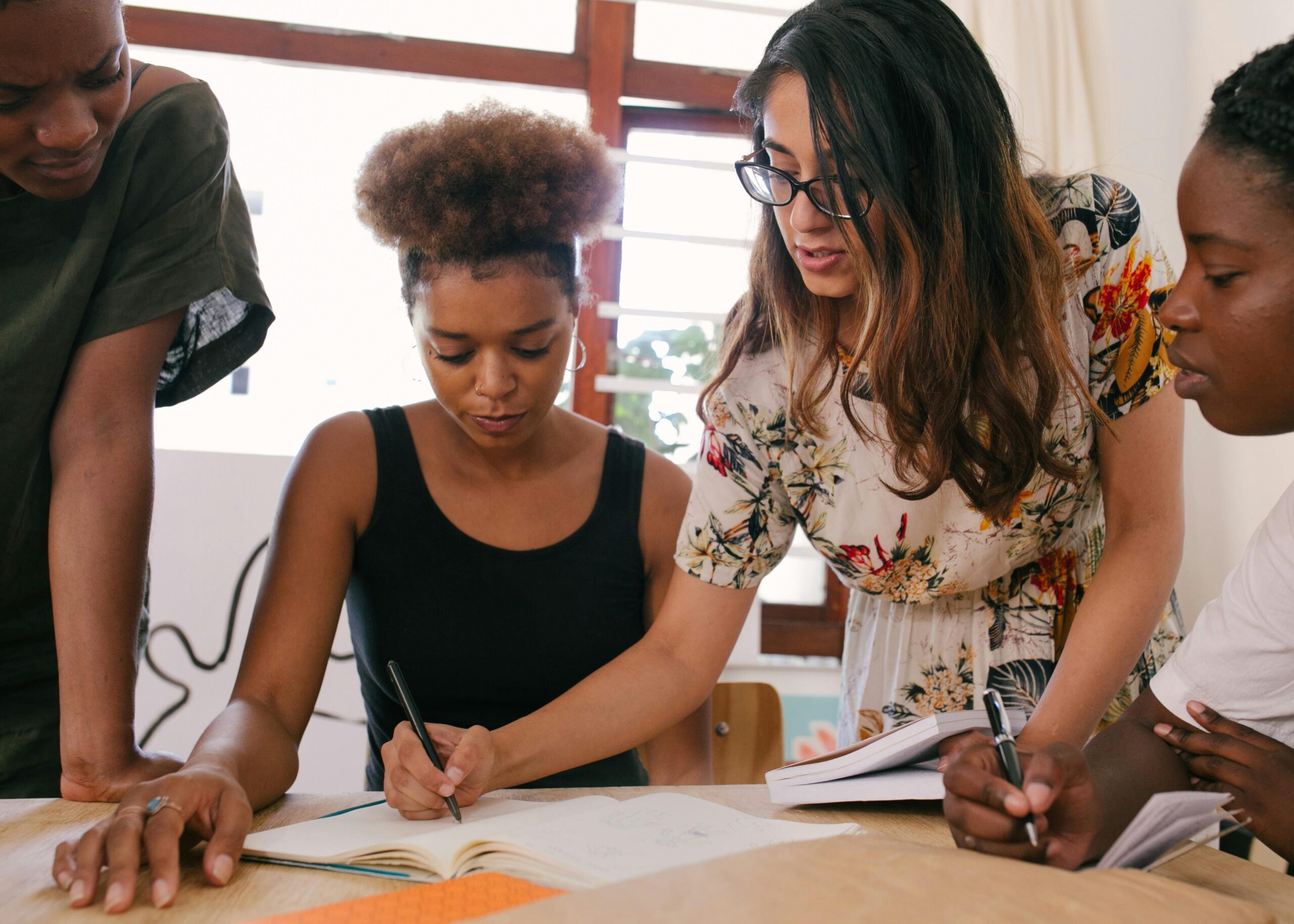 women working together at a desk jotting notes