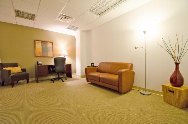 Private office at Carr Workplaces Westchester with a desk and leather lounge seating